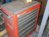 une armoire à outils rouge dans un garage, sur laquelle sont posés des outils