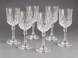six verres à vin en cristal alignés sur une surface grise