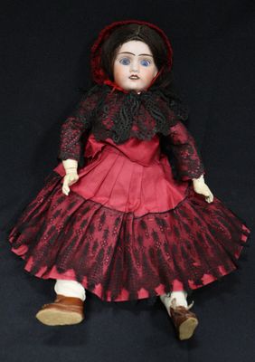 an old fashioned doll with a red dress and black hat