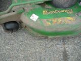 a green lawn mower that is sitting on the ground