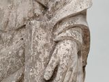 an old statue of a man holding a book and wearing gloves