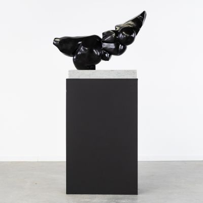 une sculpture noire représentant un oiseau perché sur un socle noir