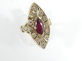 a close up of a ring with a red stone surrounded by diamonds