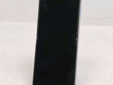 a black cell phone sitting on a stand on a white surface
