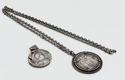 deux bijoux en argent posés sur une surface blanche