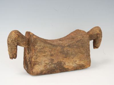 un vieil objet en bois muni d'une longue corne, posé sur une surface blanche