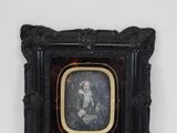 an old picture of a woman holding a baby in a black frame
