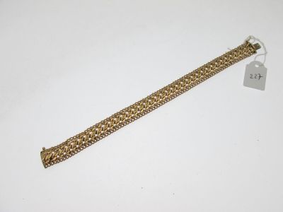 gros plan d'un bracelet en chaîne en or sur une surface blanche