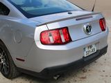 a silver mustang parked on the side of the road