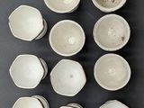 nine white bowls arranged in a circle on a table