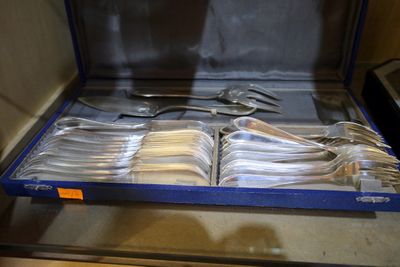 un service en argent dans un coffret bleu posé sur une table