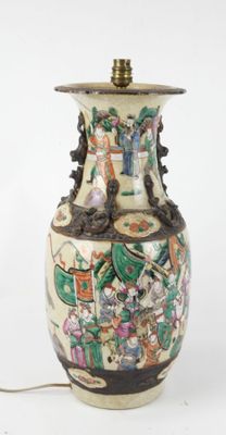 un vase blanc orné d'une peinture et sur lequel est posée une lampe