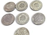 six types différents de pièces d'argent sur une surface blanche