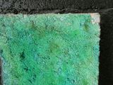 a close up of a piece of green paint on a brick wall