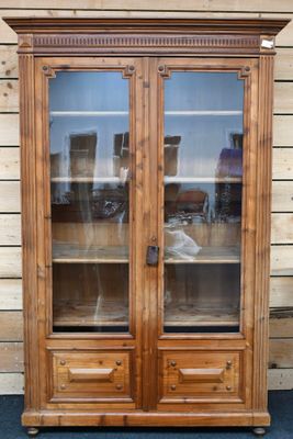 une photo d'un meuble en bois avec des portes vitrées posé sur un tapis bleu