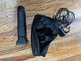 un sèche-cheveux noir et une brosse à cheveux noire posés sur un parquet