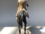 a statue of a woman riding a horse in a museum