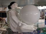 une statue représentant une femme tenant une balle, posée sur une étagère en verre