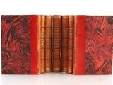 three old books with red covers are stacked on top of each other