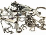 a pile of assorted silver jewelry on a white surface