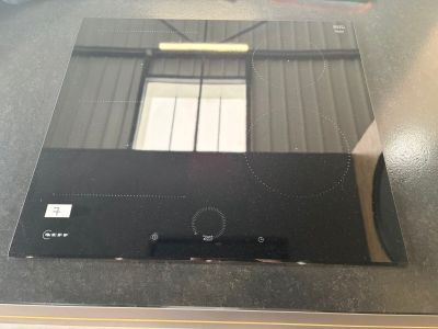 une plaque de cuisson noire avec un plateau en verre posée sur un plan de travail