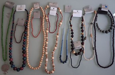 a lot of different necklaces hanging on a wall