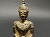a bronze statue of a seated buddha on a black background