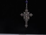 a silver cross hanging from a chain on a black background