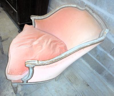 a pink chair that is sitting in front of a brick wall