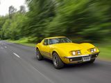 a yellow car driving down the road with trees in the background