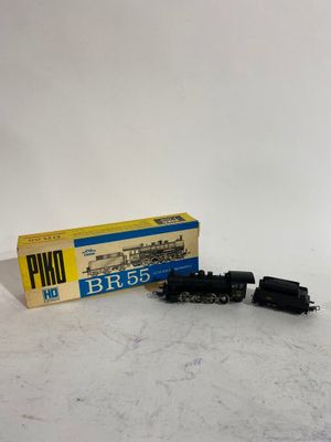 un vieux circuit de train miniature avec une boîte posée sur une surface blanche