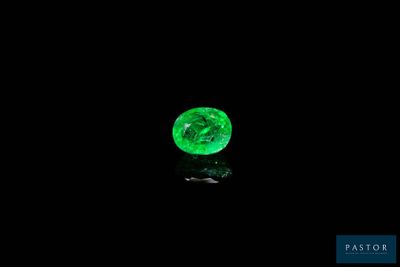 a close up of a green diamond on a black surface