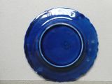 une assiette bleue accrochée au mur, sur laquelle se trouve une autre assiette bleue