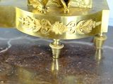 a gold clock on a marble table with a clock on top
