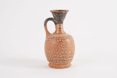 a small brown vase with a black handle on a white surface