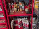 many cans of paint on a red shelf in a garage