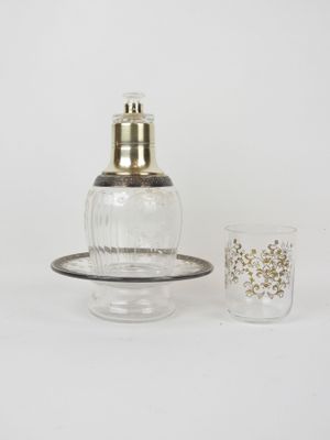 a small glass bottle with a gold lid next to a shot glass