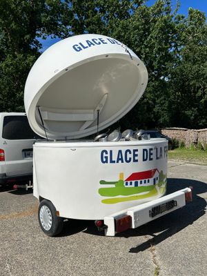 a white ice cream truck with a large container on the back of it