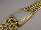 a gold watch with a chain around it on a table