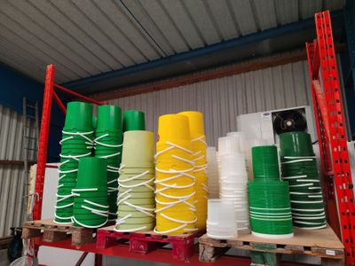Plusieurs piles de gobelets en plastique sont empilées sur une étagère dans un entrepôt