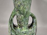 a green vase with a yellow flower inside of it