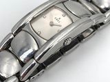 une montre en argent posée sur une surface blanche