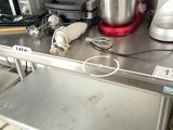 a metal counter with a metal pan and a red mixer on it