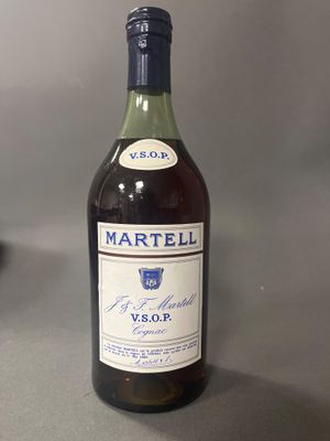 Des bouteilles de vin sont posées sur une table devant un fond gris.