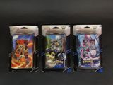 Trois paquets de cartes à collectionner Pokémon sont posés sur une surface noire.