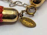 a necklace with a gold bell and a red tassel on it
