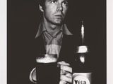 une photo en noir et blanc d'un homme assis à une table avec une bière