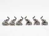 four silver elephant figurines sitting in a row on a white surface