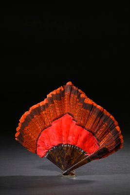 un éventail orange et noir posé sur une table