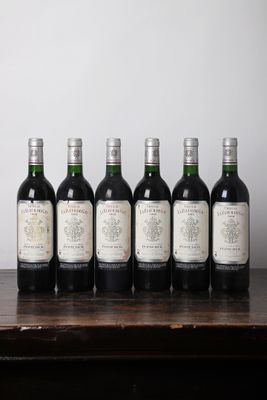 six bouteilles de vin sont alignées sur une table en bois